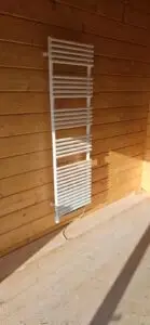 Handdoekradiator tegen een houten wand, project Sanitair bungalow