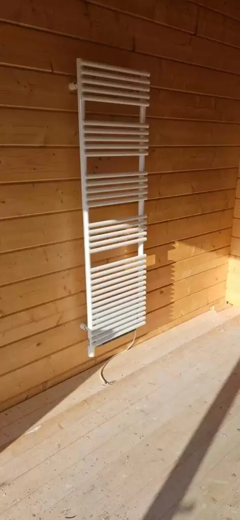 Handdoekradiator tegen een houten wand, project Sanitair bungalow