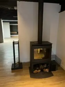 Houtkachel met houtopslag in een lichte ruimte, realisatie Aqua & Fire
