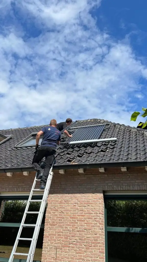 Technieker plaatst collectoren op het dak, project Zwembadverwarming met heatpipe systeem