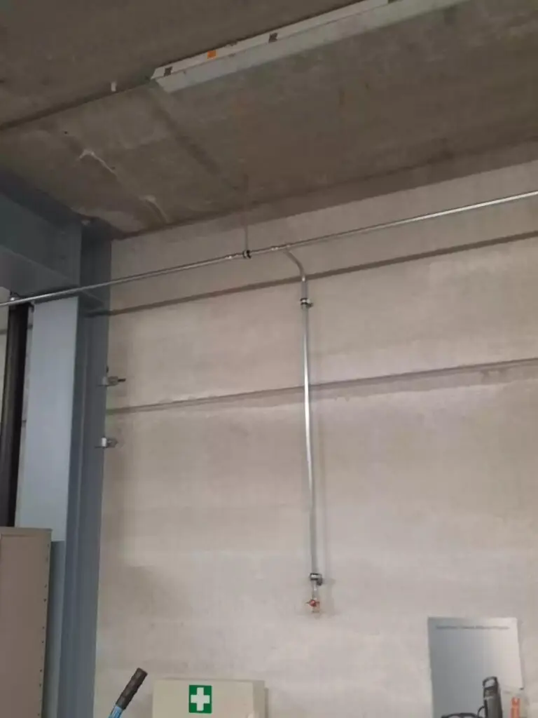 Persluchtleiding langs de wand van de hal, project Luchtdruk leiding plaatsen