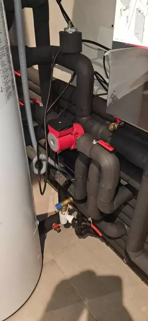 Geïsoleerde leidingen naast een boiler, project Isolatiewerken Wessels